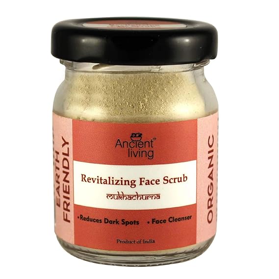 A glass jar with a black lid containing Ancient Living Organic Revitalizing Face Scrub. The label is orange and white with text and branding.